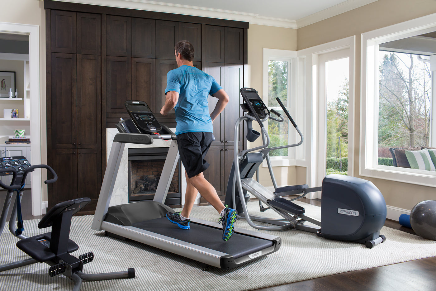 Man running on a Precor TRM 445 treadmill in his home gym that also includes a Precor EFX 447 elliptical and a 240i StretchTrainer