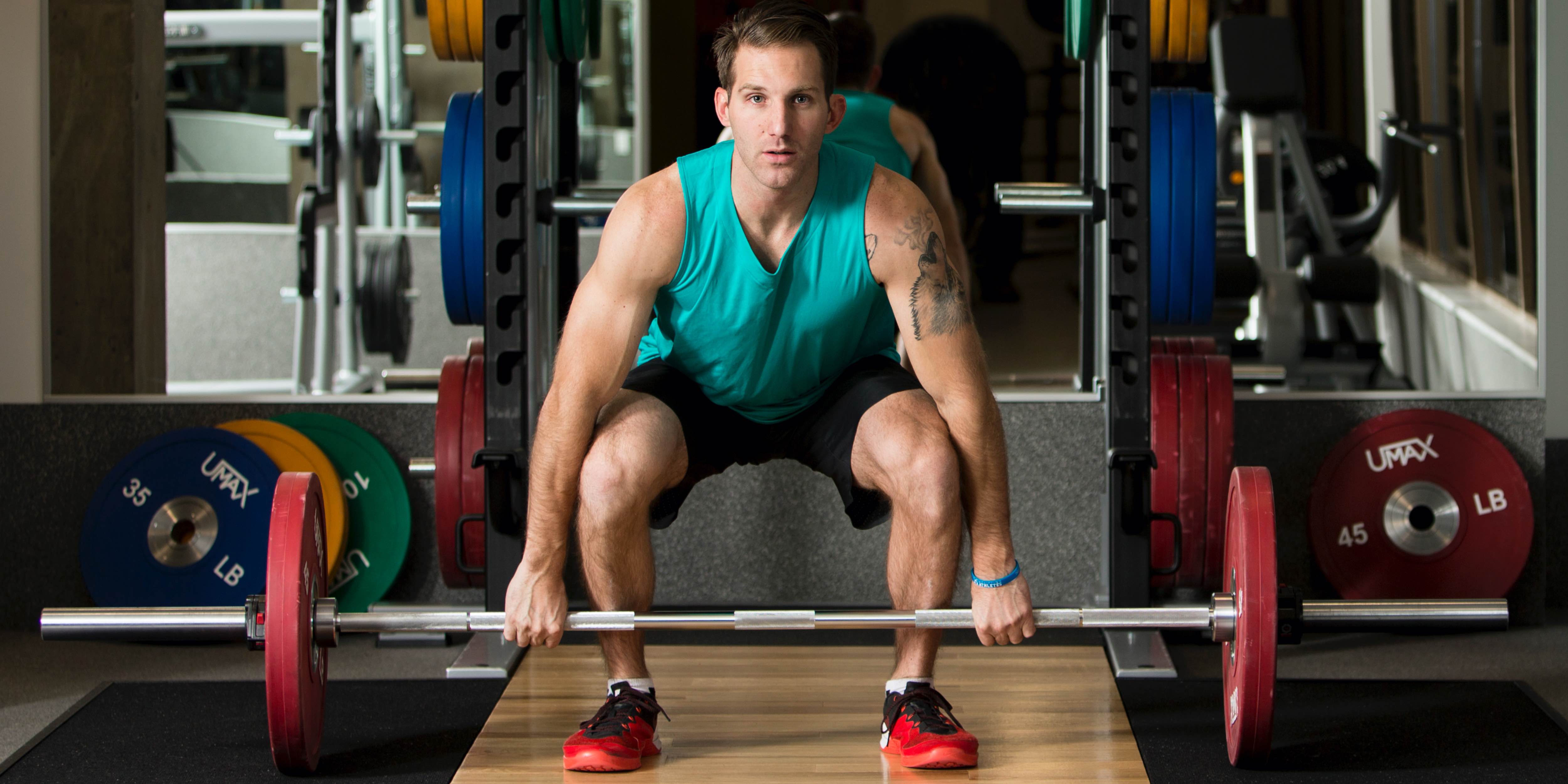 male exerciser deadlifting weights with Precor power rack for strength training