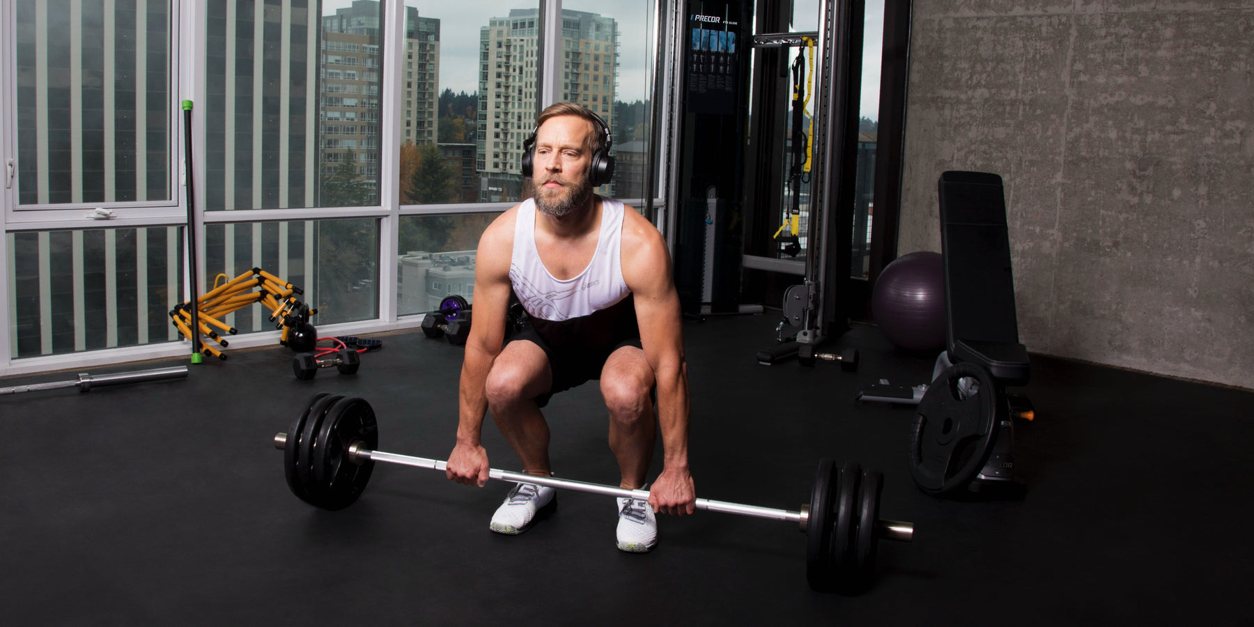 Male exerciser strength training with barbell deadlift using Precor strength equipment