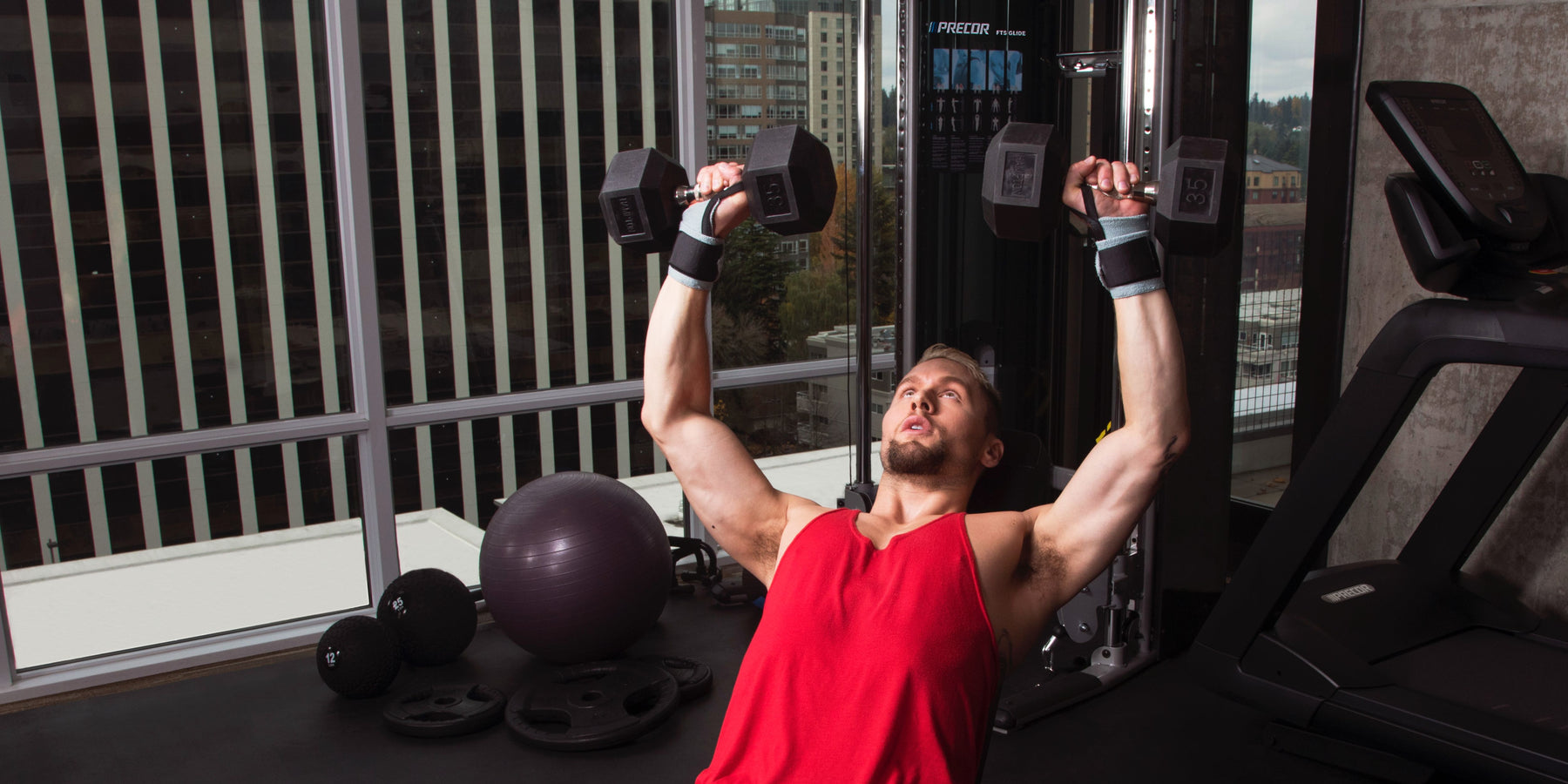 male exerciser strength training with incline press using Precor dumbbells and bench